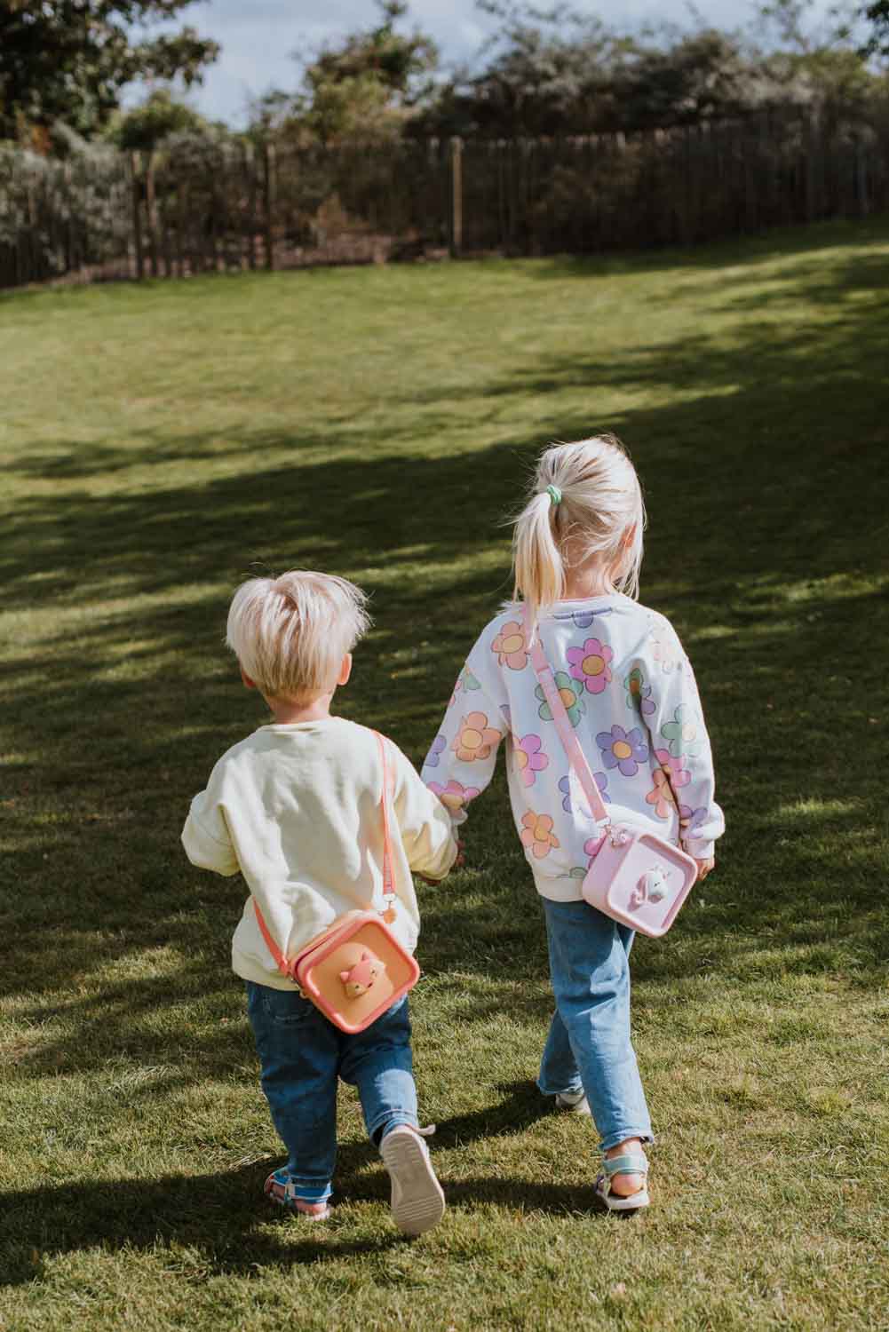 silicon bag fox and unicorn, kids are carrying the bags around their neck while walking hand in hand in the garden
