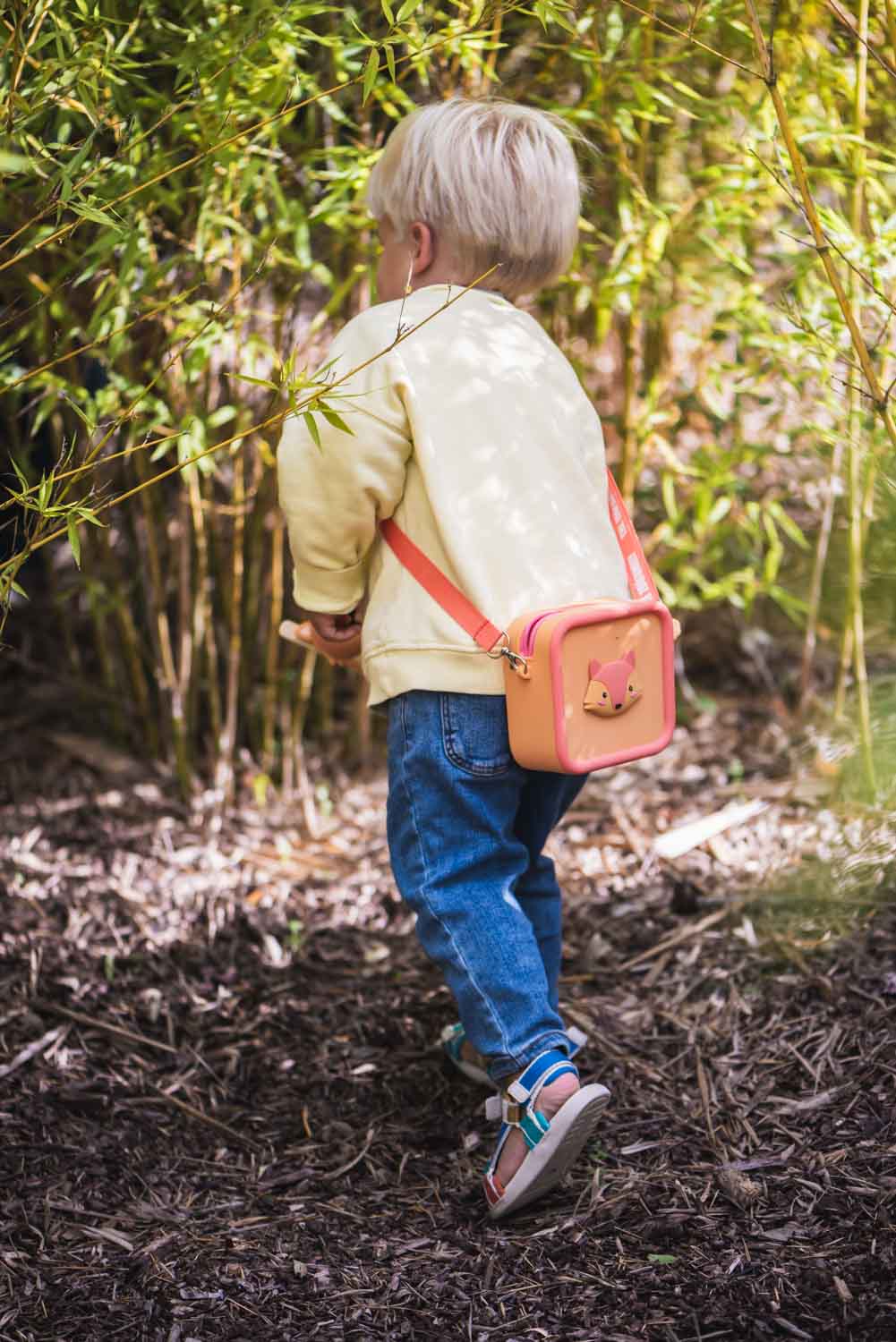 silicon bag fox, child is carrying the bag over its shoulder while walking between the bushes