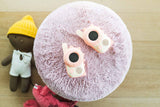 odalzoo walkie talkie set dino pink, lying on a pillow with cuddles aside